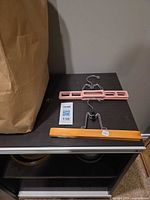Wooden clamp hanger and pink plastic clamp hanger on shelf next to bag