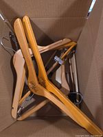 Top-down view inside carton showing mixed wood and plastic hangers with metal hooks and clips