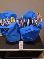 Two blue bags filled with assorted plastic hangers in various colors