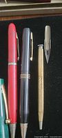Close-up of right side items (red pen, grey pen, gold pencil, nib)