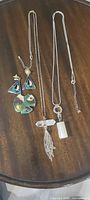 Full lot overview on tabletop showing earrings pair, matching pendant, two necklaces with different pendants