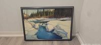 Full framed painting leaning against wall showing winter river scene