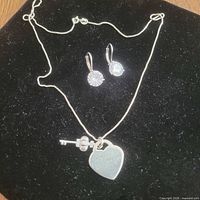 Full view of necklace and earrings on black background