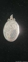 Front of sterling silver floral engraved oval locket pendant