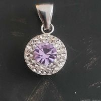Front view of pendant showing purple center stone and clear halo