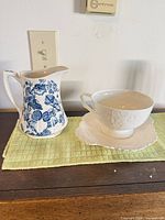 Pitcher, cup and saucer together on surface