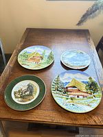 Four decorative wall plates on table