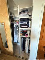 closet view with folded clothing stacks and hanging garments