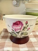 Front view of ceramic bowl on wood base showing rose design