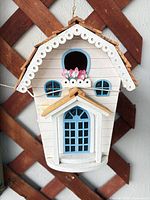 Front view of white and blue wood birdhouse with flowers and hanger