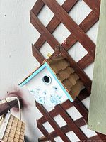 Overall view of birdhouse hanging on trellis