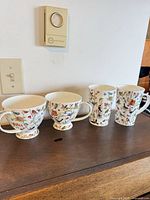 Two footed teacups and two tall mugs on tabletop