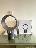 Fan, remote, power cord and box on tabletop