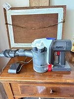 Dyson handheld vacuum with wand attachment and charger on table