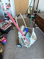 Side view of folding wire shopping cart with canvas liner, ruler and miscellaneous items shown for scale only