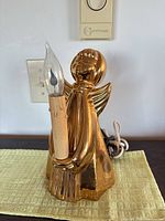 Full view of gold glazed ceramic angel lamp with bulb installed