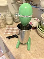 Front view of mint green Hamilton Beach drink mixer with stainless cup
