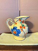 Full side view of pitcher showing floral design and pedestal base