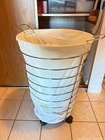 Full view of chrome wire laundry hamper with liner and casters