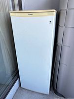 Front view of Kenmore upright freezer showing single door, brand badge and yellowed trim