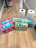 Group shot of five Kleenex hand towel boxes in assorted patterns with two loose paper towel rolls