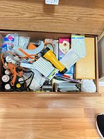 Drawer view showing glue guns, glue sticks, flashlight, wire spools, boxed items