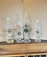 Front view of all four glass oil lamps with chimneys