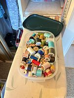 Overview of plastic tub filled with assorted thread spools