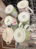 Six floral mugs top view in dishwasher rack showing patterns and some maker stamps