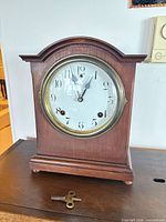 Front view of wood mantel clock with brass bezel and dial