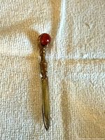 Full view of brass letter opener front side on fabric background