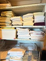Stacks of white, cream and green towels on closet shelves