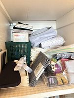 Shelf with folded linens, clothes shaver box, basket and pouches