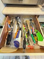 Open drawer showing all utensils arranged in three clear trays