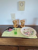 All items on dresser: pair gold busts, floral plate, black dish, green uranium glass tumbler