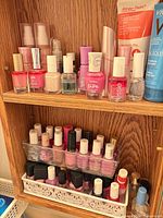 Two shelves holding numerous nail polish bottles in organizer and tray