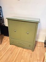 Full front view of olive green dresser with glass panel on top showing doors and bottom drawer