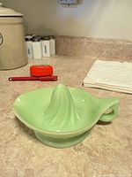 side view showing entire opaque green glass citrus reamer with handle and spout