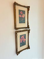 Both framed prints hanging vertically on wall