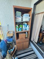 Full view of cabinet on balcony showing two shelves with plastic bins on top and lower cupboard