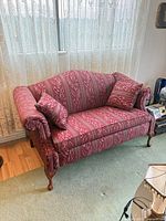 Full front view of loveseat showing upholstery, two pillows, overall form