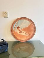 Full view of round wall plaque leaning against wall