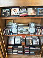 Full cabinet view showing Sanyo stereo, speakers, CDs and cassette tapes