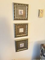 Three framed floral artworks hung vertically on wall