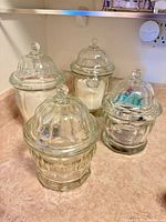Four clear glass canisters with domed lids on countertop