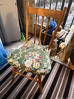 Front angled view of chair showing spindle back, cushion, legs