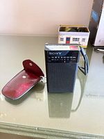 Front view of Sony ICF-P26 radio beside red leather pouch