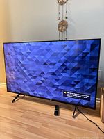 Front view of Sony KD-50X85K TV powered on with remote visible