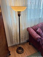 Full view of torchiere floor lamp beside furniture