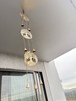 Full view of hanging brass-tone wind chime showing three medallions and bells